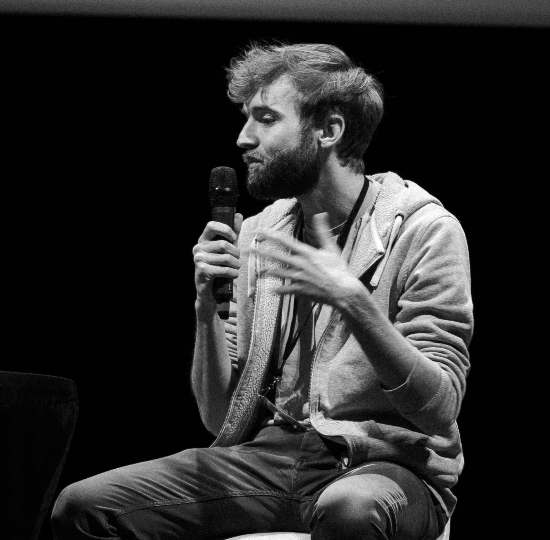 Valentin Bertrand, micro à la main, en pleine intervention sur scène (photo noir et blanc).